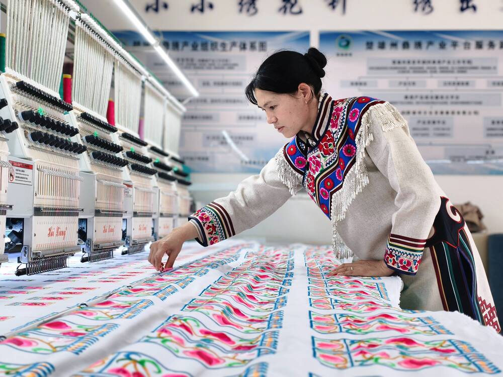 15.彝绣工坊里的绣娘在加工机绣绣片.jpg 15.彝绣工坊里的绣娘在加工机绣绣片.jpg